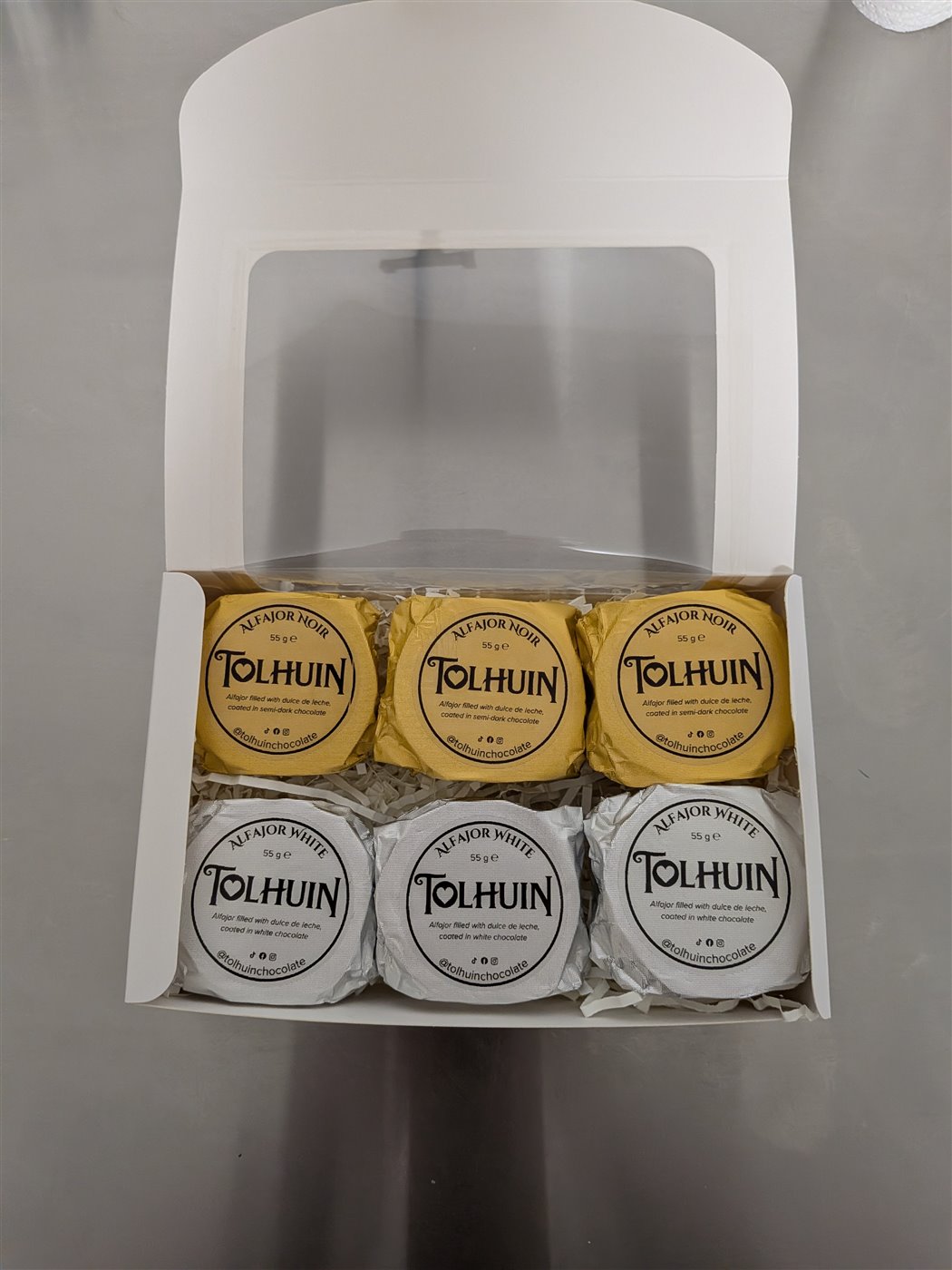 An open Tolhuin box filled with wrapped alfajores